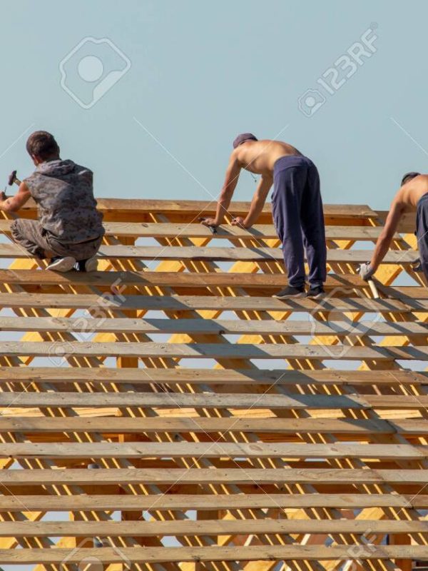 Workers are building the roof of the house from wood.
